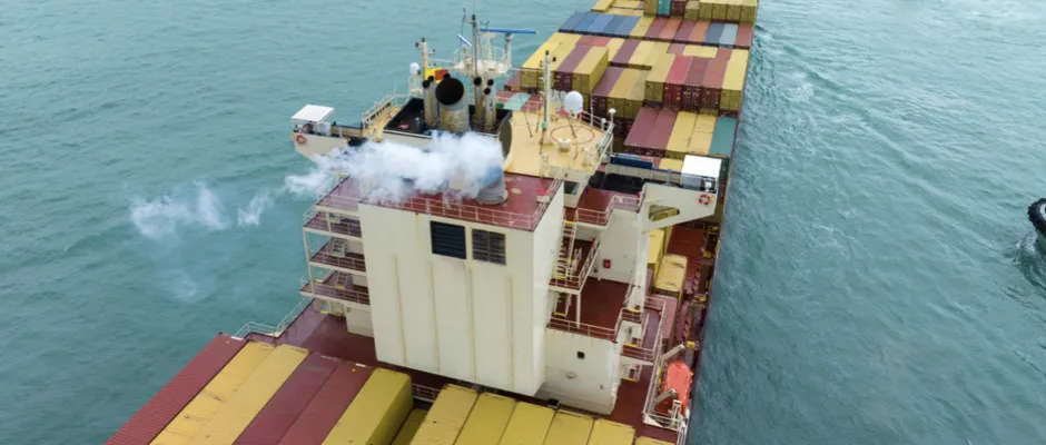 Loaded container ship emitting visible exhaust under EU ETS in international maritime transport