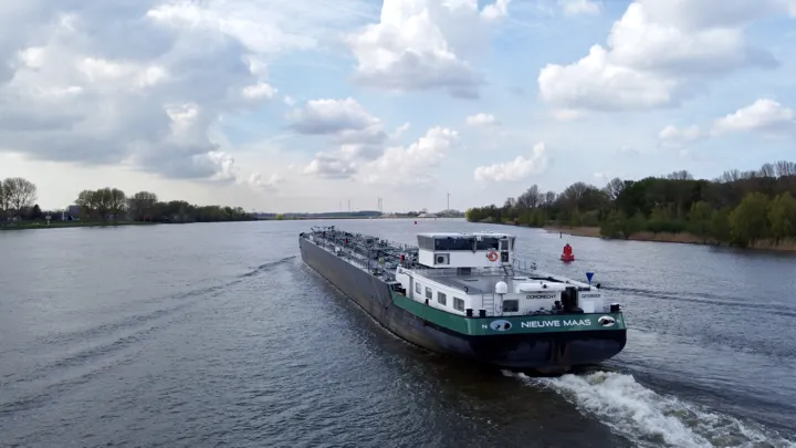 Binnenvaarttanker Nieuwe Maas met CFD-geoptimaliseerde straalbuizen, varend op een rivier voor maximale efficiëntie en duurzaamheid.